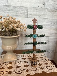 a small wooden christmas tree sitting on top of a table next to a potted plant