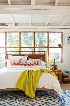 a bed with white sheets and pillows in a bedroom next to a blue rug on the floor