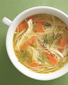 a white bowl filled with soup and carrots on top of a green tablecloth