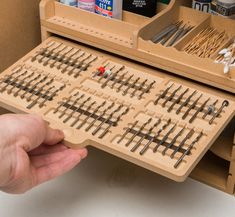 a person is holding a wooden box with many different types of train tracks in it