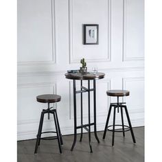 two stools and a table in front of a white wall