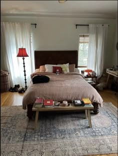 a bed sitting on top of a wooden floor next to a table with two lamps