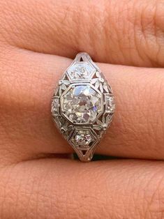 a woman's engagement ring with an old cut diamond in the center, on her finger