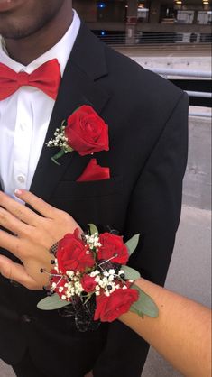 a man in a tuxedo and red bow tie with flowers on his lapel