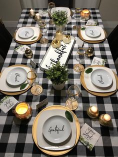 a black and white checkered table cloth with place settings on it, along with candles