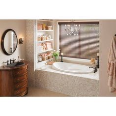 a bathroom with a tub, sink and mirror next to a shelf that has towels on it