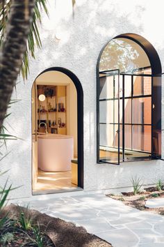 a bathroom with an arched window and tub in the doorway to another room that is outside