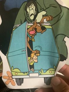 a person holding up a sticker with an image of scooby on it