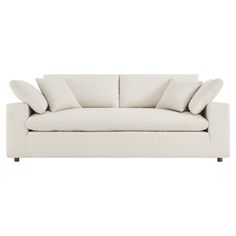 a white couch with four pillows on it's back and one arm facing the camera