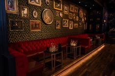 a room with red couches and pictures on the wall behind them, along with small tables