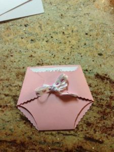 a pink card with a white bow on it sitting on top of a marble counter