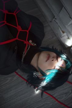 a woman with blue hair and black clothes is laying on the floor next to a red rope