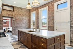 a kitchen with an island in front of two windows and a door leading to another room