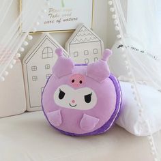 a pink and purple stuffed animal sitting on top of a white bed next to pillows