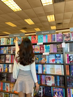 a woman standing in front of a book shelf filled with books