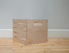 a wooden crate sitting on top of a hard wood floor next to a white wall