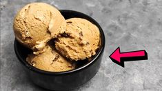 two scoops of ice cream in a black bowl with an arrow pointing to it