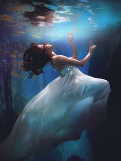 a woman in a white dress floating under water