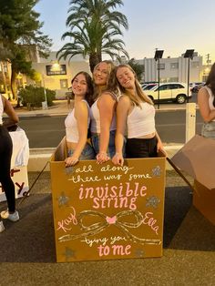 three girls are standing behind a sign that says, we are always some invisible spirits you may say to me