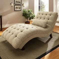 a chaise lounge chair sitting on top of a rug in front of a window