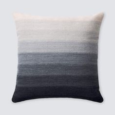 a black and white pillow with grey stripes on the front, sitting against a gray background