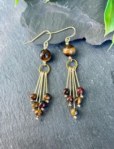 Make a statement with our Tiger's eye earrings! These eye-catching dangle earrings showcase natural tigerseye gemstones hanging beautifully from a golden hoop, giving you a unique and stylish vibe. Perfect for casual outings or special events, these earrings bring a natural charm to any outfit. EARRING FEATURES Total Length: Approximately 2.5 inches Gemstone: Tigerseye 4mm & 8mm  Metal: Gold Tone ♥ All orders come beautifully hand-packaged with care, making it the perfect gift for yourself or someone special. ♥ Each piece is handmade with love in my home studio in Rockaway, NJ. Fringe Beaded Earrings, Boho Jewelry Diy, Lampwork Bead Jewelry, Tiger Eye Jewelry, Gold Fringe, Jewelry Making Earrings, Crafts Jewelry, Earrings Dainty, Eye Earrings