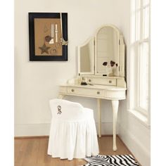 a white dressing table and mirror in a room with zebra rugs on the floor