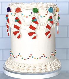 a white cake decorated with candy canes and christmas stocking hanging from it's sides