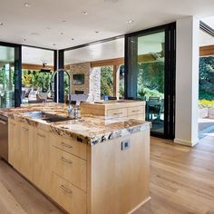 a kitchen with wooden cabinets and marble counter tops, along with an island in the middle