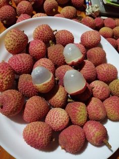 a white plate topped with lots of fruit on top of a wooden table next to other plates