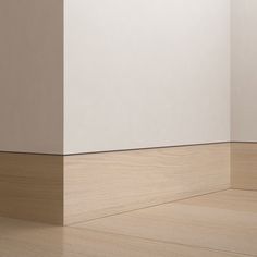 an empty room with white walls and wood flooring on the side, in front of a beige wall