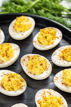 deviled eggs with mustard and parsley on a black plate, ready to be cooked