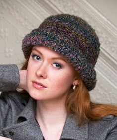 a woman with red hair wearing a gray coat and a knitted beanie hat