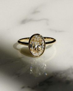 a yellow diamond ring sitting on top of a marble counter