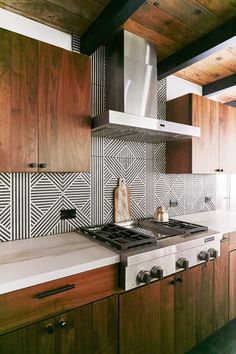 a stove top oven sitting inside of a kitchen next to wooden cupboards and counter tops