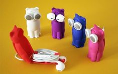 four toy animals with headphones on sitting next to each other, all in different colors