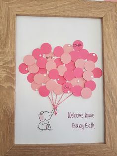 a wooden frame holding a pink heart shaped balloon with the words welcome home baby birth written on it