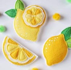 three felt lemons with green leaves and yellow ones on white table top next to each other