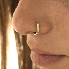 a close up of a woman's nose with a gold nose ring on it