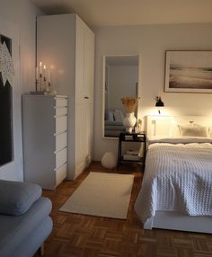 a bedroom with white bedding and wooden flooring next to a dresser in the corner