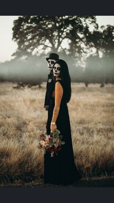 a man and woman in skeleton makeup standing next to each other on a field with tall grass