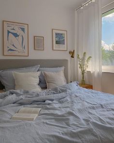 a bed with blue sheets and pillows in a bedroom next to two pictures on the wall