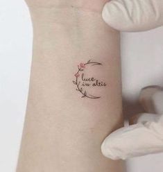 a woman's wrist with a small tattoo saying love is in the air on it