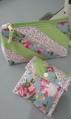 two small purses sitting on top of a table next to each other, one with flowers