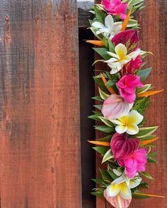 flowers are arranged on the side of a wooden fence