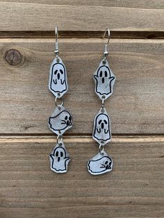 three ghost earrings hanging from a wooden surface