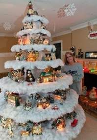 a woman standing in front of a christmas tree with snow on it's bottom