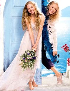 two beautiful young women standing next to each other in front of an open blue door