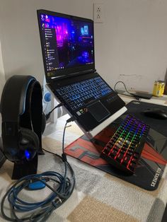 an open laptop computer sitting on top of a mouse pad next to a gaming headset