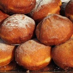 a pile of doughnuts sitting on top of a glass tray covered in powdered sugar